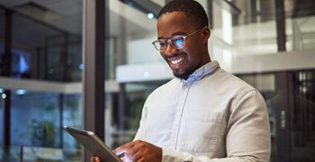 Man smiling while working on tablet in office