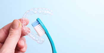 Patient holding clear aligner and toothbrush