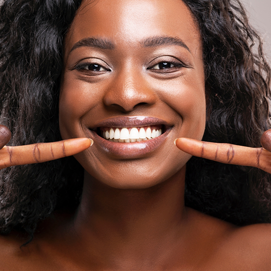 Woman pointing to her smile with flawless teeth