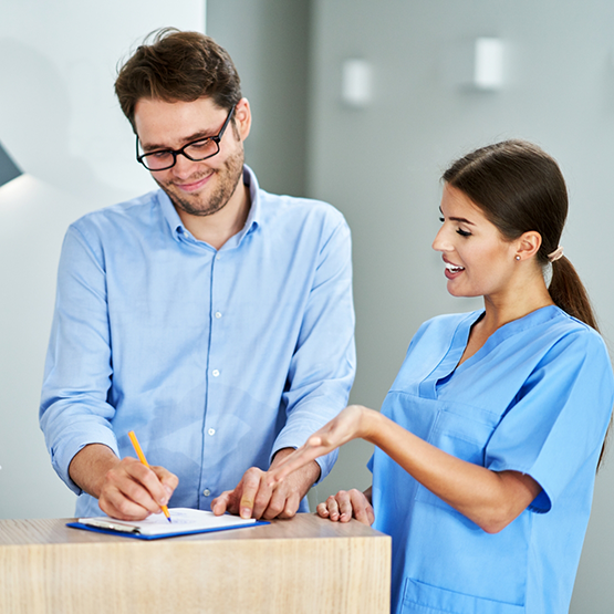 Dental team member showing a patient where to sign on a clipboard