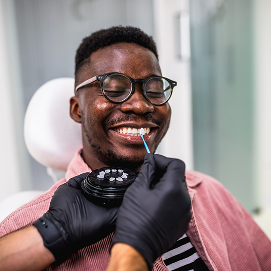 Dentist holding a veneer in Tallahassee in front of a smiling patient